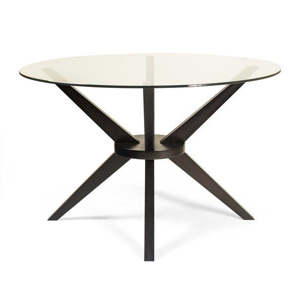 A round table with a glass top and wooden legs that form an “X” brace when viewed from any side. 