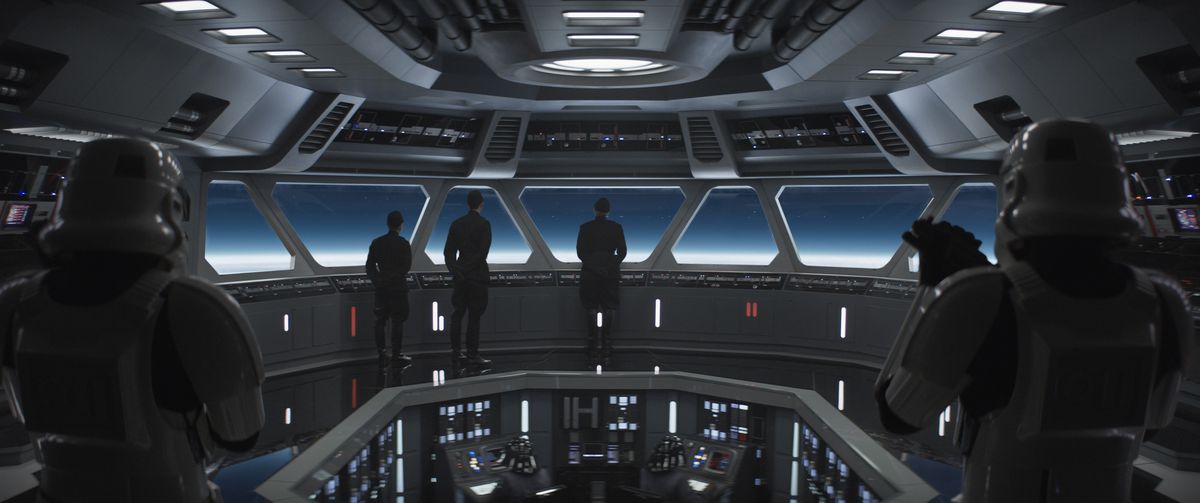 Imperial officers and Stormtroopers stand on a Cantwell-class Arrestor Cruiser while looking out the front window in Andor.