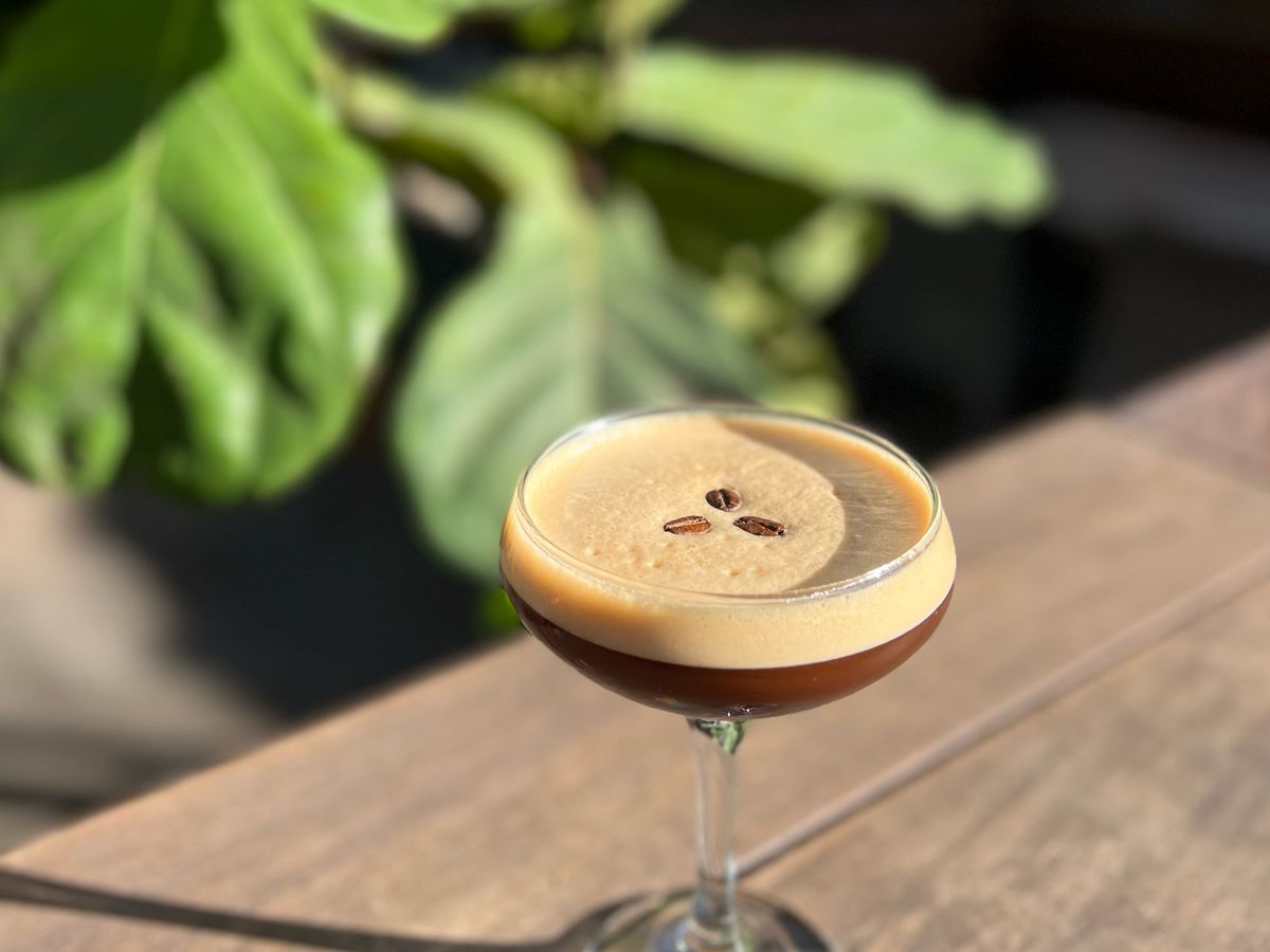 An espresso martini garnished with espresso beans pictured outside on the patio at Brasil.
