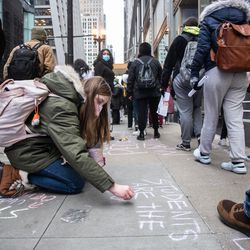 Hailey Carter, 18, a senior at Northside College Prep, writes “students are the future” outside the Chicago Public Schools headquarters in the Loop during a district-wide walkout to demand Mayor Lori Lightfoot, Chicago Department of Public Health Dr. Allison Arwady and Chicago Public Schools CEO Pedro Martinez to include them in the conversation about COVID-19 safety in schools, Friday afternoon, Jan. 14, 2022. Many students advocated for remote learning and stood with the Chicago Teachers Union which has been pushing for improved COVID-19 safety protocols in schools.