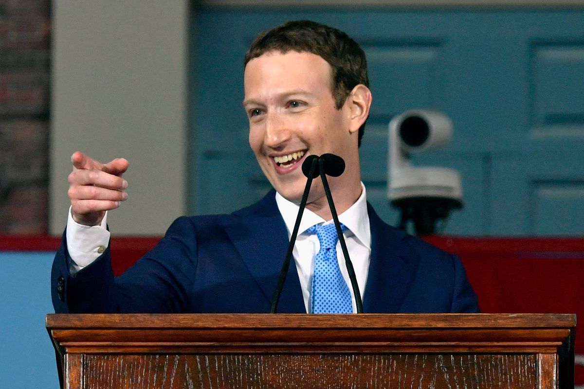 Facebook CEO Mark Zuckerberg smiles and points from a podium where he is giving a speech.