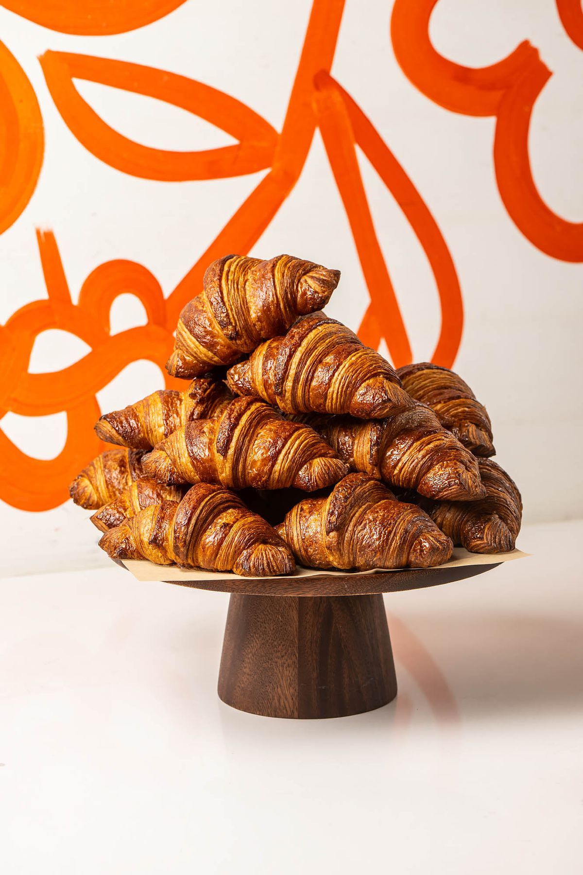 A risen wooden platter with a stack of dark brown croissants at LA bakery Friends &amp; Family.