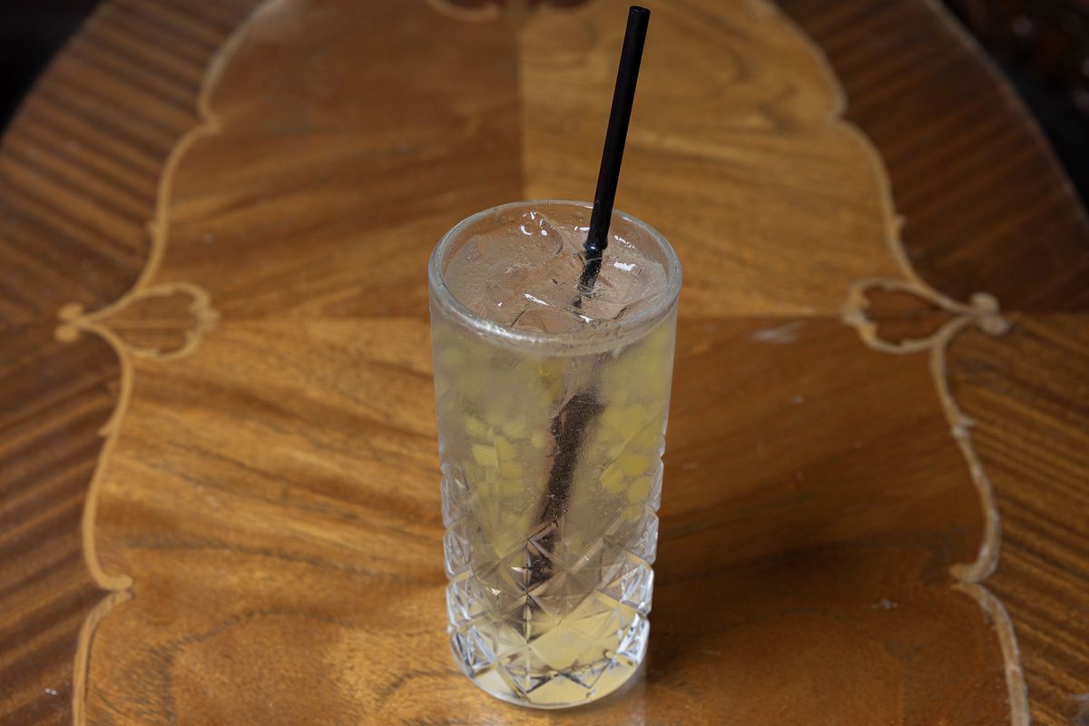 A clear cocktail with yellow sake pearls inside.