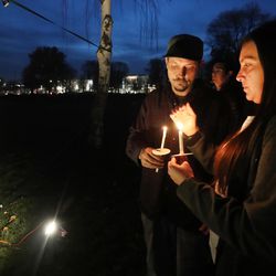 Alyssa Sallee and Jeremiah Giles hold candles near a list of 121 homeless men and women who died during the year during a candlelight vigil in Salt Lake City on Thursday, Dec. 20, 2018, at Pioneer Park.