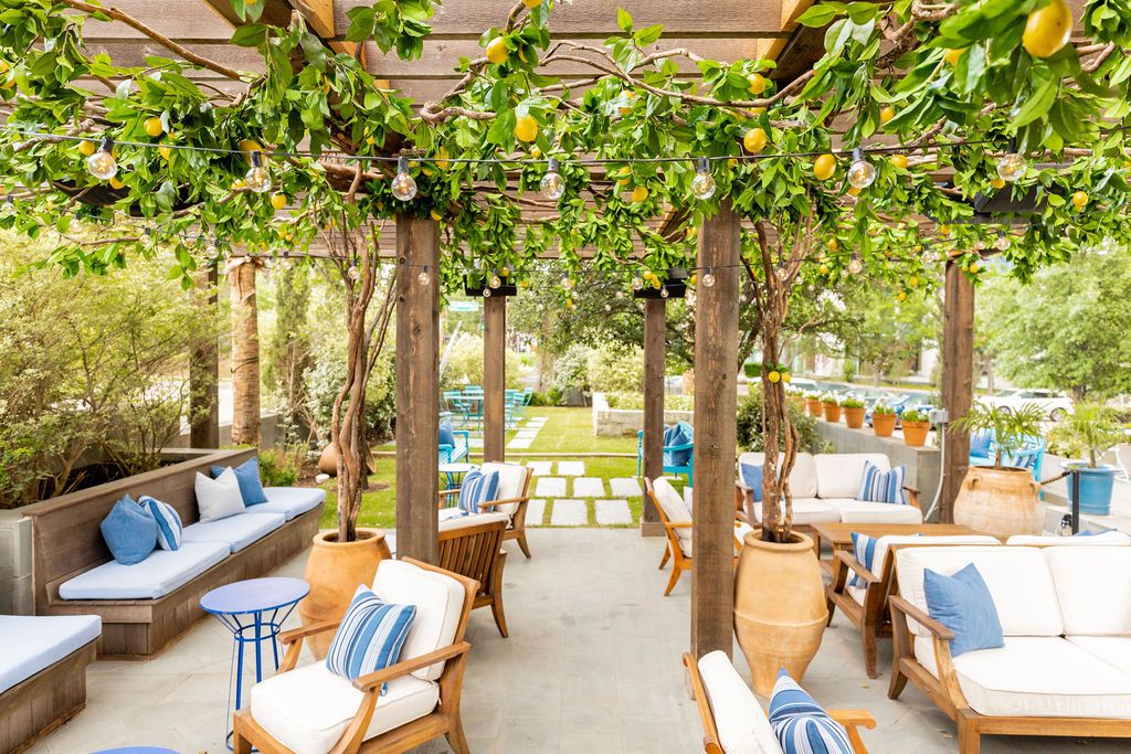 Lemon trees add a sense of freshness to the patio at Dolce Riviera. Seats with white and blue cushions rest under them.