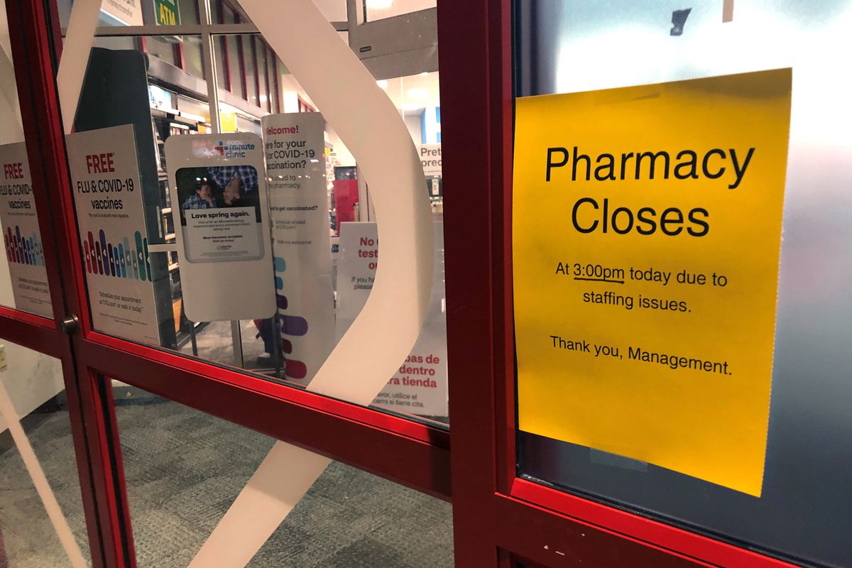 A sign posted outside a CVS pharmacy in Indianapolis warns customers of early closings. A rush of COVID-19 vaccine-seeking customers and staff shortages are squeezing drugstores around the country.
