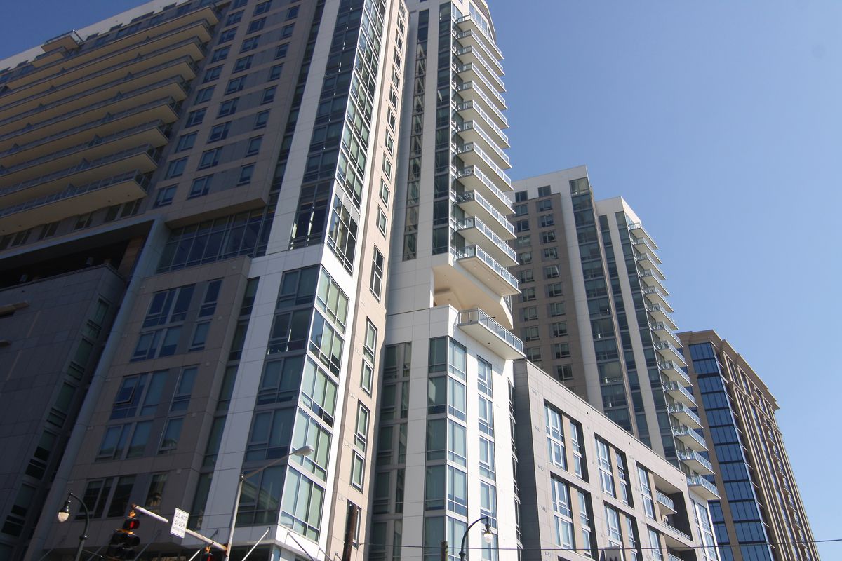 Two tower developments show in the sunshine, with balconies and many glassy windows.