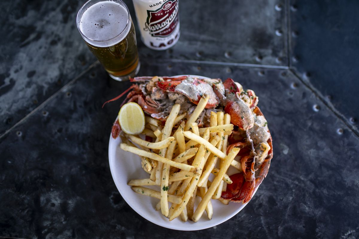 A plate of boiled lobster and fries with a beer