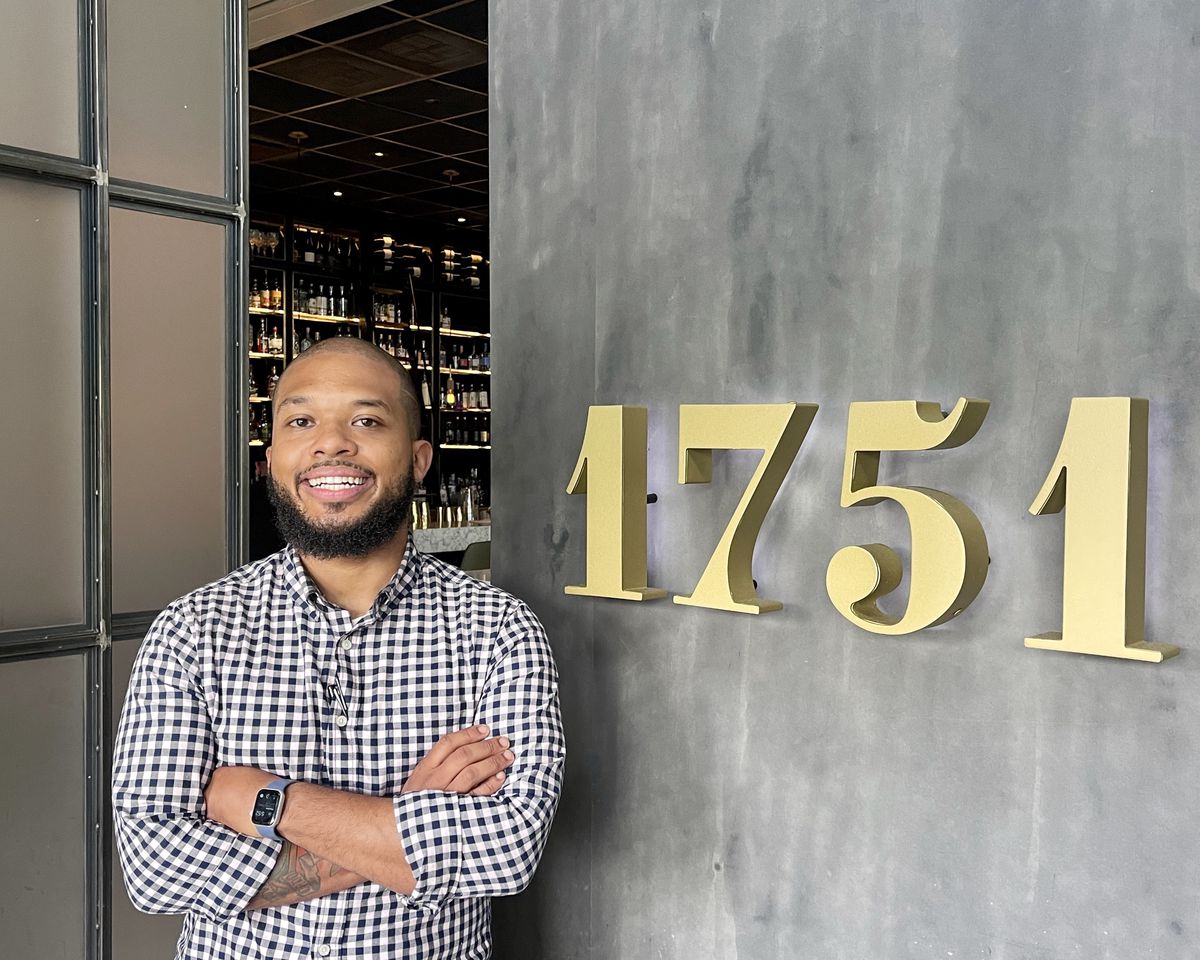 Chef Matthew Young in front of 1751 Sea and Bar’s sign.