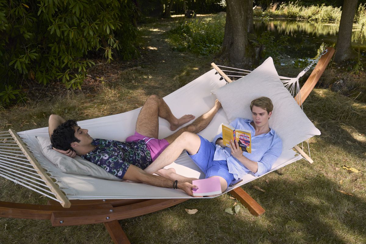 Nicholas Galitzine and Taylor Zakhar Perez lounge in a hammock together while reading a book in Red, White &amp; Royal Blue.