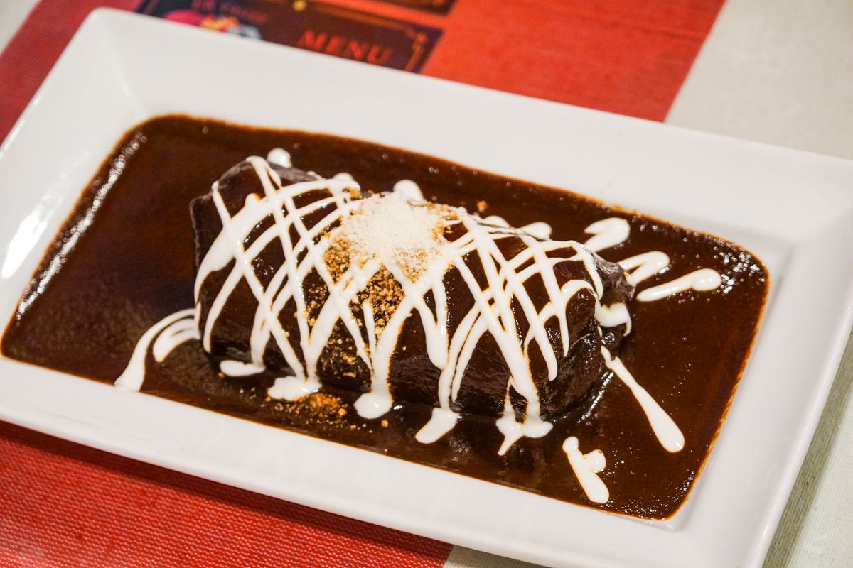 A black mole covered burrito with crema mexicana.
