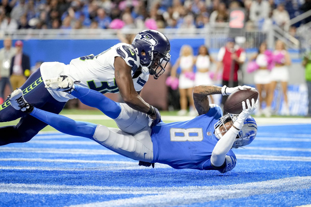 Josh Reynolds #8 of the Detroit Lions scores a touchdown against Mike Jackson #30 of the Seattle Seahawks during the fourth quarter of the game at Ford Field on October 02, 2022 in Detroit, Michigan.