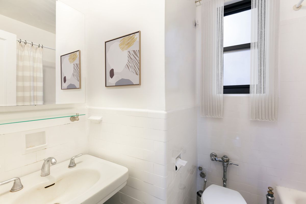 A bathroom with white walls and tiles.