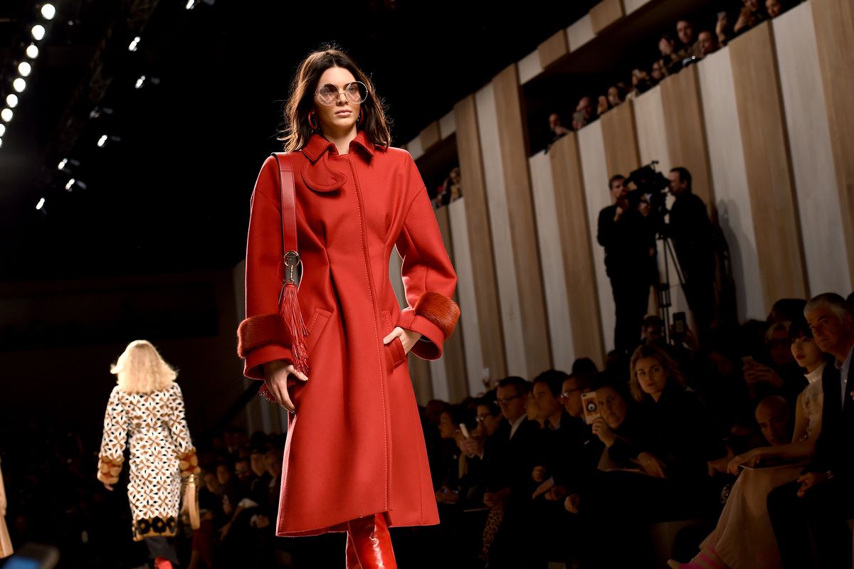Kendall Jenner in a Carmen Sandiego-like red trenchcoat.