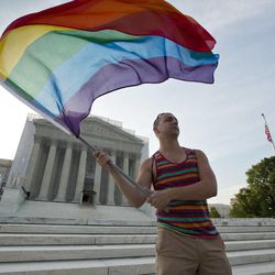 Gay rights advocate Vin Testa waves a rainbow flag in front of the Supreme Court at sun up in Washington, Wednesday, June 26, 2013. Justices are expected to hand down major rulings on two gay marriage cases that could impact same-sex couples across the country. One is a challenge to California's voter-enacted ban on same-sex marriage. The other is a challenge to a provision of federal law that prevents legally married gay couples from receiving a range of tax, health and pension benefits. 