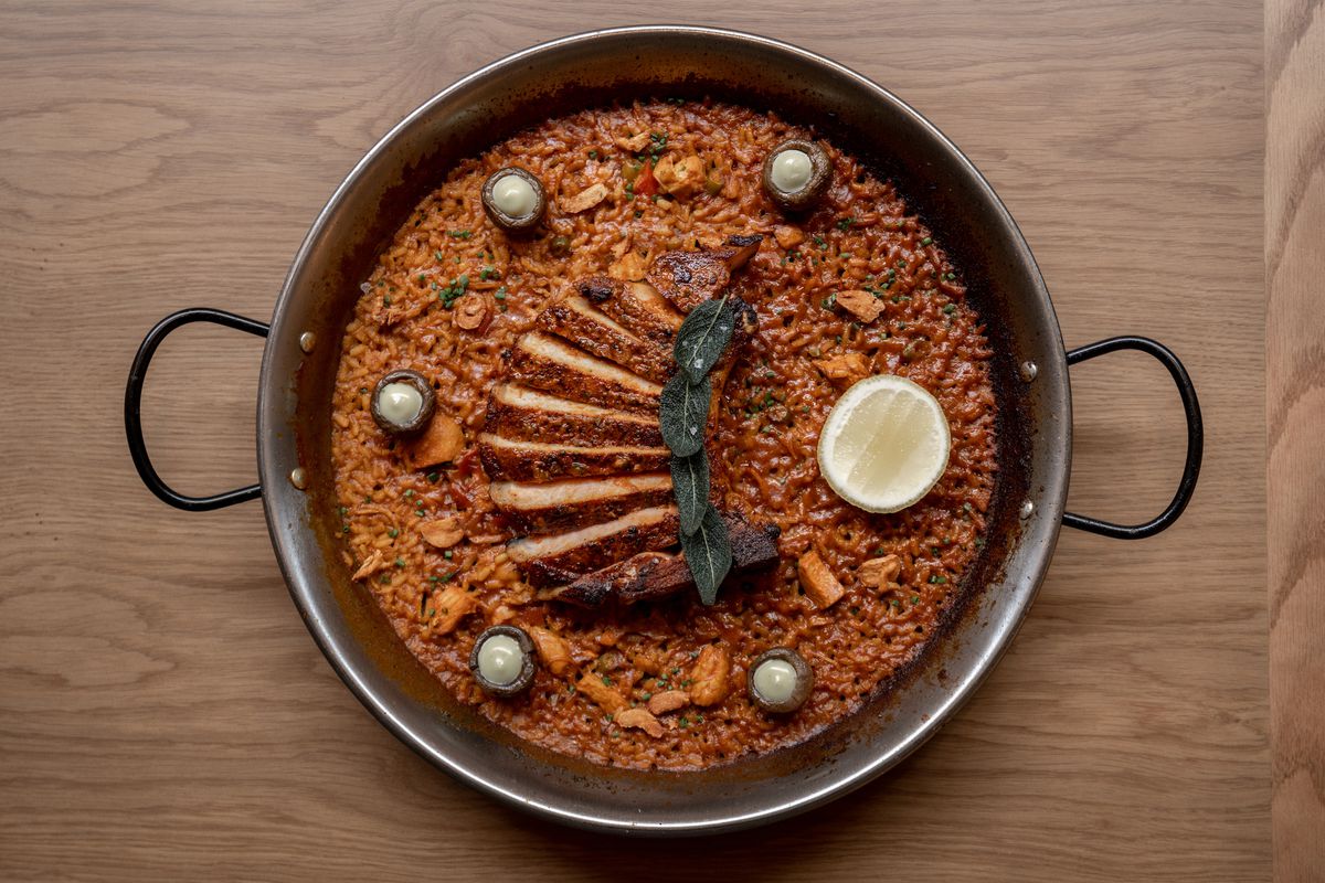 An overhead shot of sliced pork with fried green sage on paella at the new Telèferic.