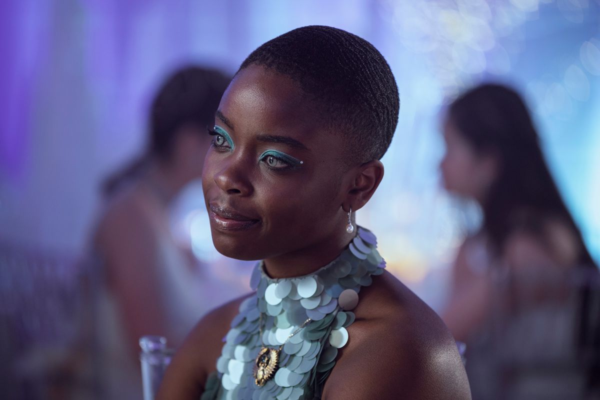 bianca, a black girl with pale blue eyes lined with matching silvery-blue eyeliner, looks at someone during the school dance. she wears a sparkly silver-blue outfit 