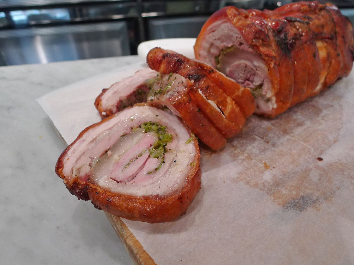 A skin on bronze colored pork roast cut in thick slices.