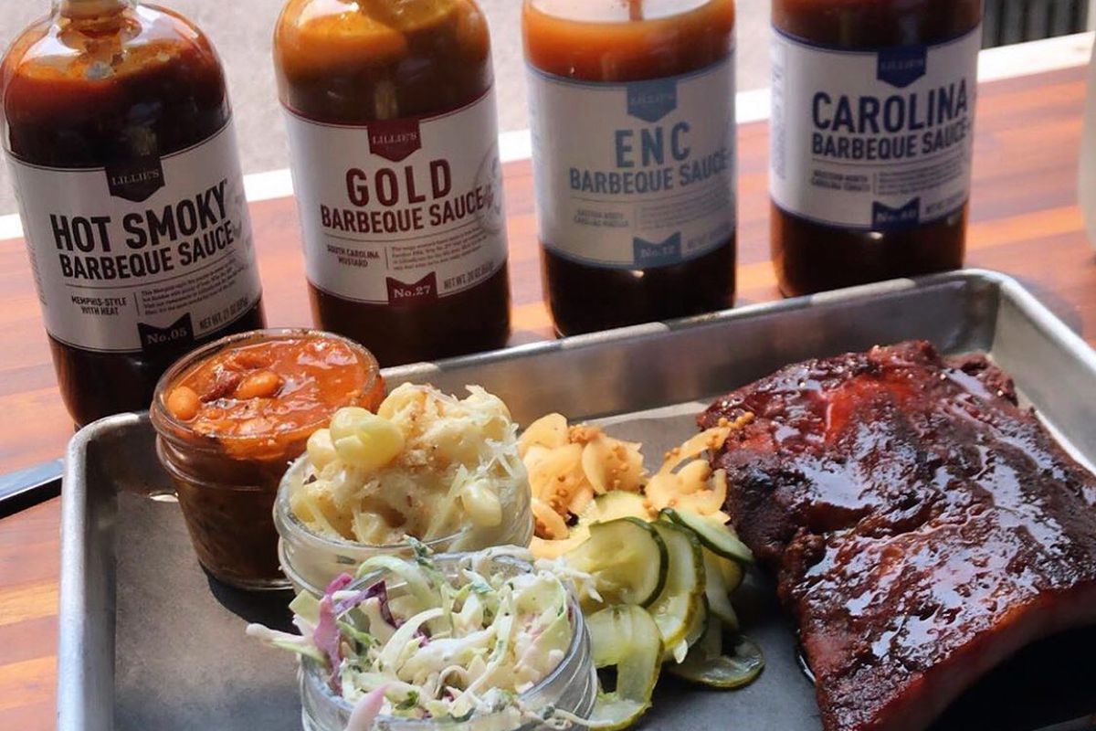 Bottles of barbecue sauce behind a platter of ribs.