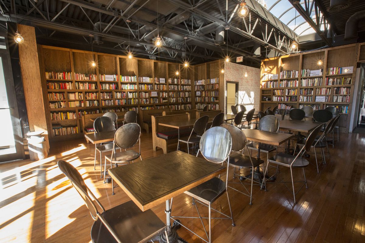 A bar/restaurant surroudned by books with a skylight.