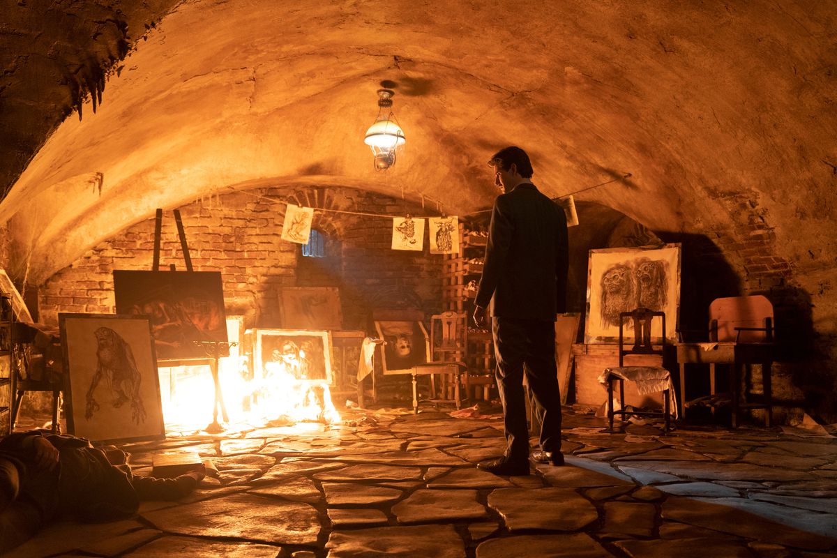A man (Ben Barnes) stands in basement surrounded by portraits of horrific creatures, engulfed in flames.