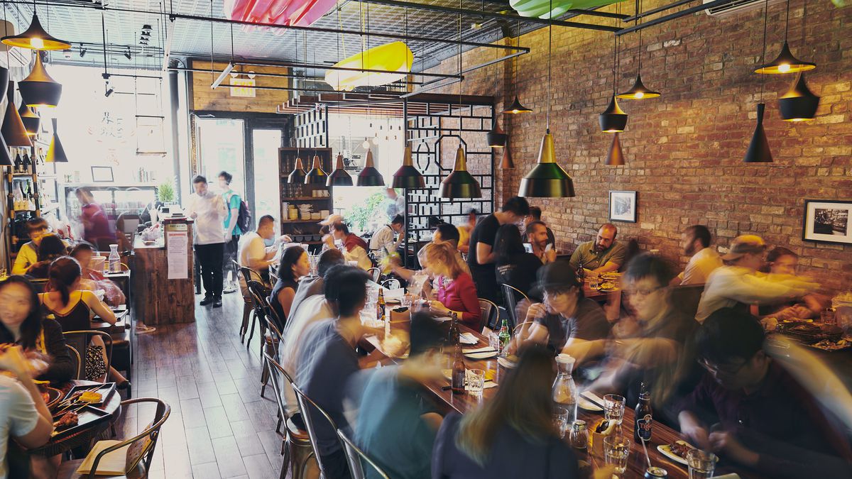 Le Sia’s busy dining room full of customers and an exposed brick wall