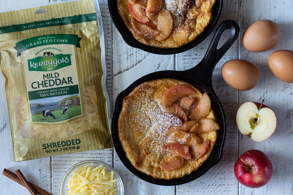 A bag of Kerrygold shredded cheddar cheese and a Dutch Baby pancake in a cast iron pan