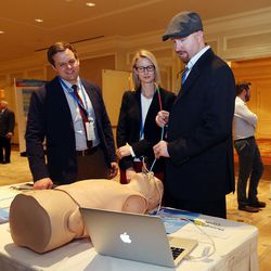 Benjamin Fogg, left, and Mackenzie Hales, center, of Through the Cords, watch as Bryce Hansen uses a color-coded steerable introducer during the Governor's Utah Economic Summit in Salt Lake City on Friday, April 15, 2016. The aim is to make intubation safer for patients and more streamlined for professionals.