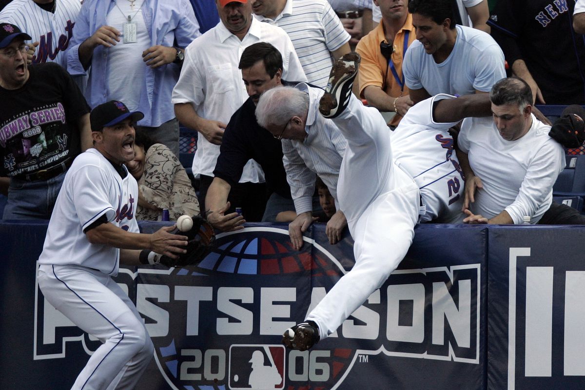 New York Mets first baseman Carlos Delgado falls into the stands trying to catch a foul ball hit by
