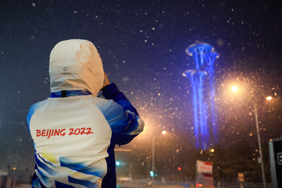 A volunteer takes picture of the Olympic Tower in the snow outside the Main Media Center of the Beijing 2022 Winter Olympics on January 30, 2022 in Beijing, China.