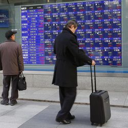 A man watches an electronic stock indicator in Tokyo Wednesday, Feb. 4, 2015. Asian stock markets rose Wednesday after a jump in oil prices helped push U.S. shares sharply higher and Japanese economic data showed improvement.  Japan's Nikkei 225 stock index surged 342.89 points or 1.98 percent and closed at 17,678.74. 