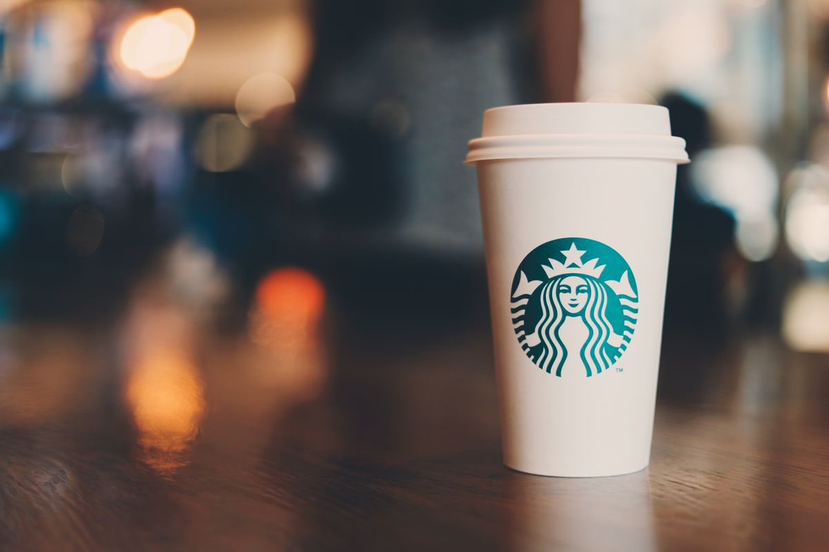 A Starbucks cup on a wooden table with a blurry background.