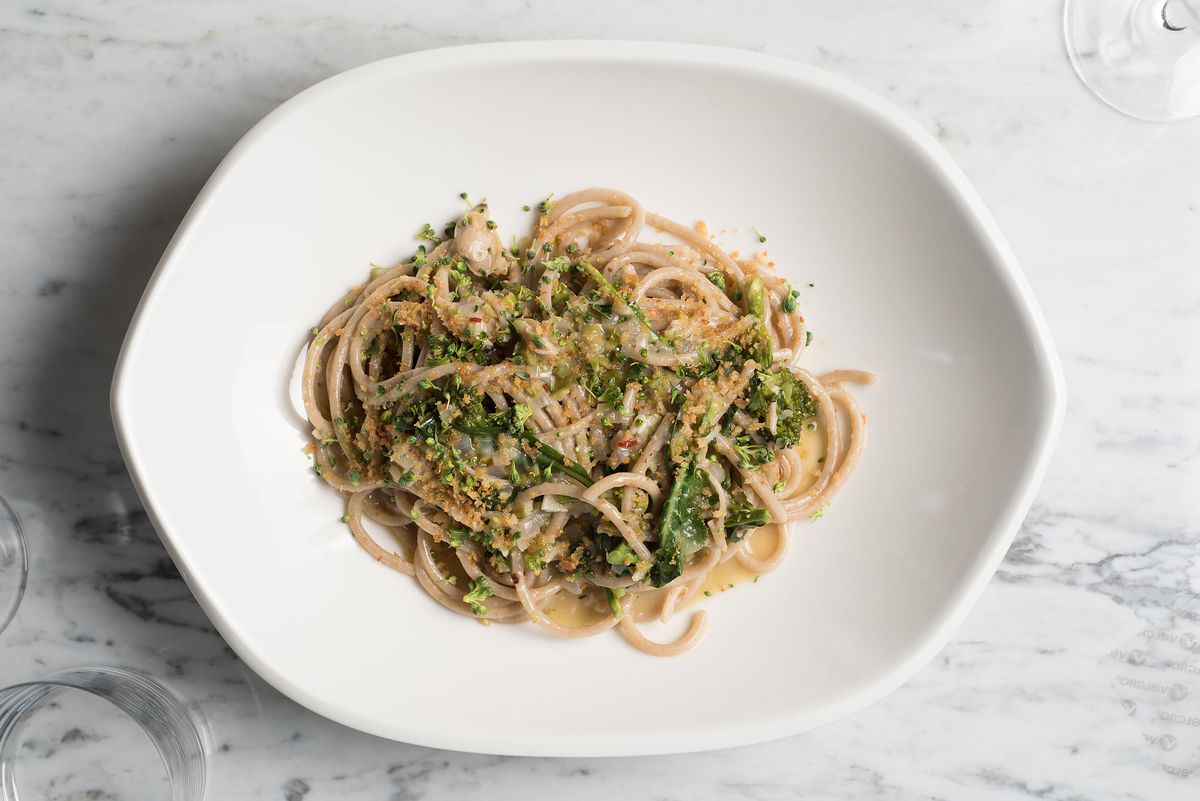 A plate of pasta with greens on a marble table at Cal Mare.
