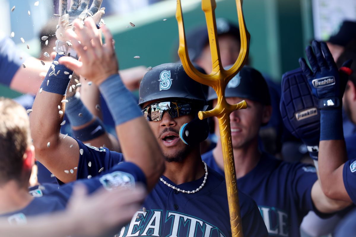 Julio Rodriguez of the Seattle Mariners is congratulated by teammates in the dugout after hitting a 3-run home run during the 8th inning of the game against the Kansas City Royals at Kauffman Stadium on August 17, 2023 in Kansas City, Missouri.