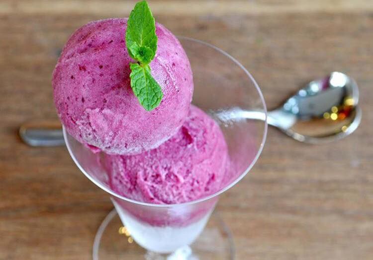 Bright purple ice cream in a dish, topped with mint.