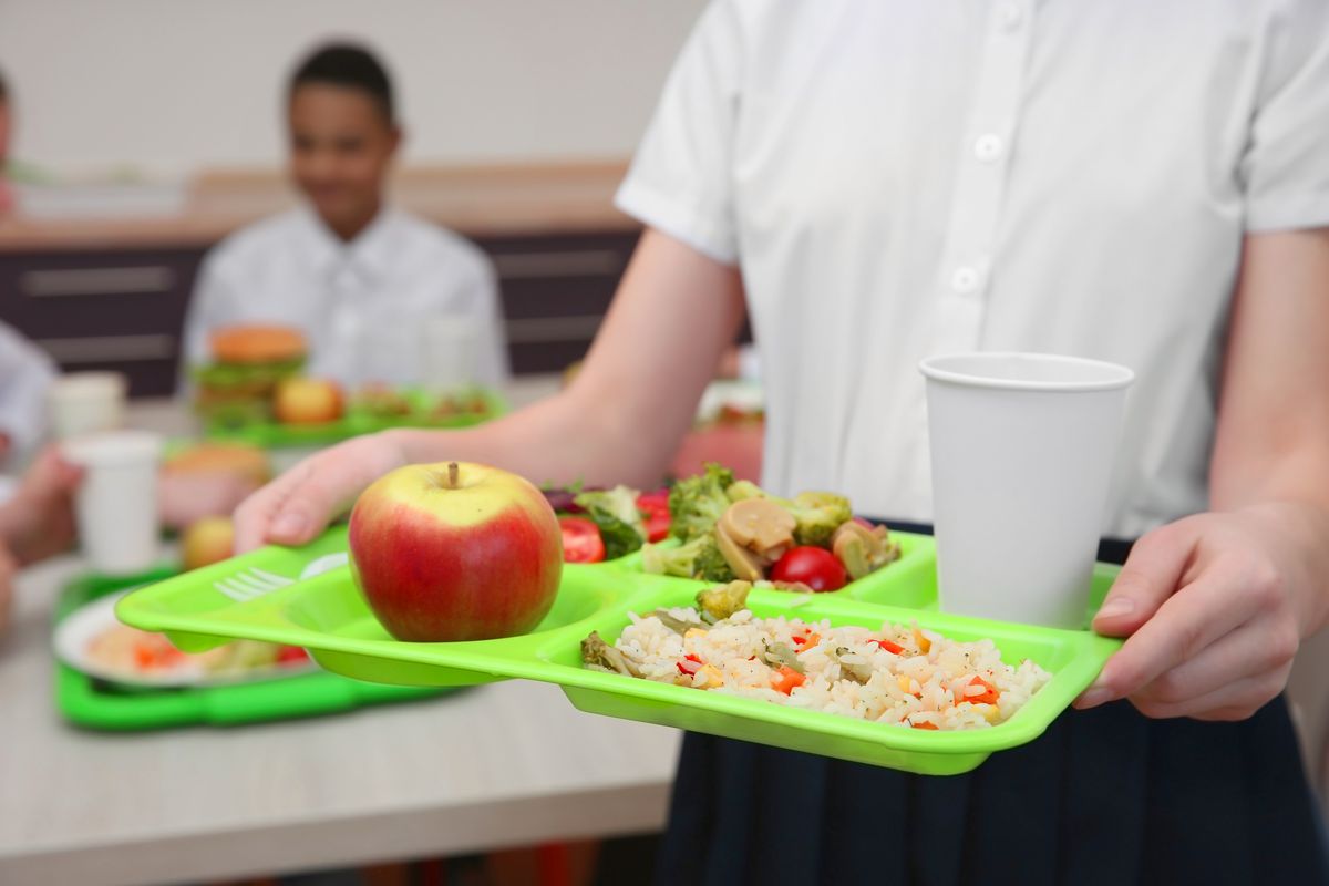 A student holding a tray of food in a school cafeteria.