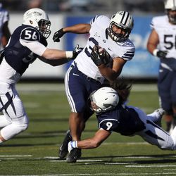 BYU's Paul Lasike, center, tries to run through Nevada's Alex Bertrando (56) and Matthew Lyons (9) during the first half an NCAA college football game in Reno, Nev., on Saturday, Nov. 30, 2013.