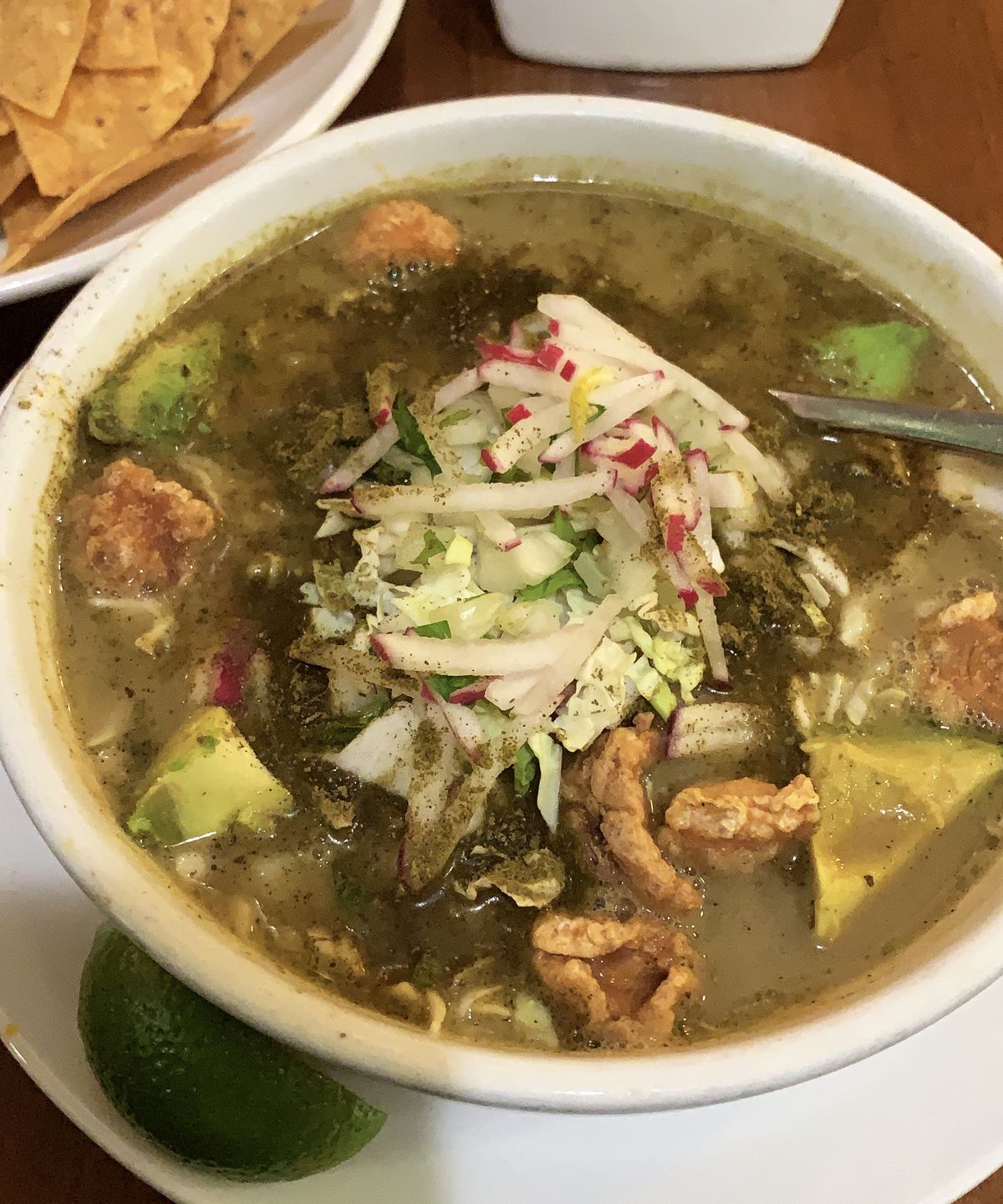 A big bowl of pozole topped with chicharron and radish.