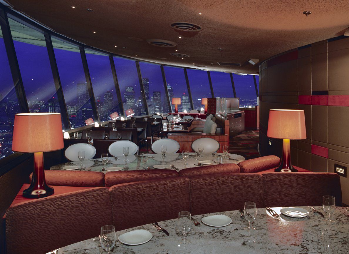 A view of the low-lit dining room in the currently-closed SkyCity Restaurant, featuring nighttime views of the city and banquettes.