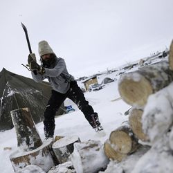 In this Tuesday, Nov. 29, 2016 photo, Blackhorse Shasta, of Oregon, chops wood on the Oceti Sakowin camp where people have gathered to protest the Dakota Access pipeline near Cannon Ball, N.D. Camp dwellers are getting ready for the hardships of a long stay. Mountains of donated food and water are being stockpiled, as is firewood, much of which has come from outside of North Dakota, the least-forested state in the nation. 