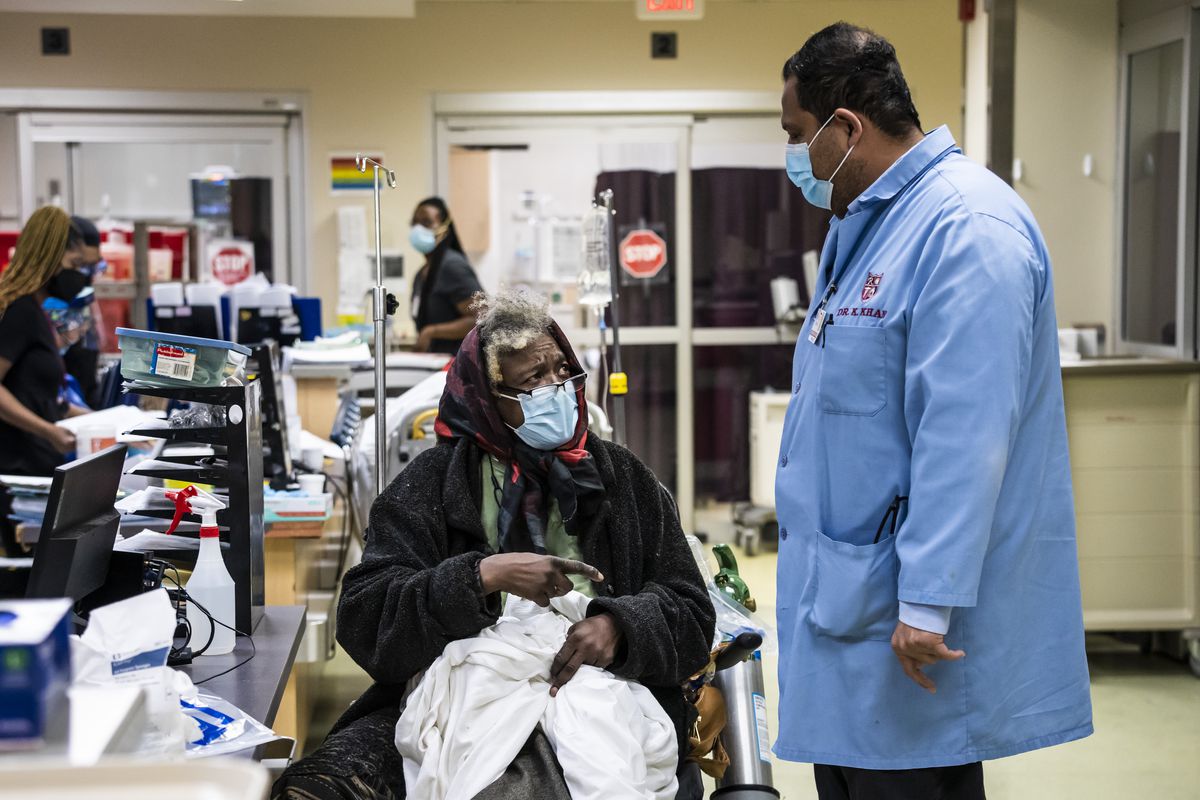 Chief medical officer Dr. Khurram Khan chats with 75-year-old Connie Edwards, who arrived with a swollen leg due to complications from diabetes, in the hallway, as no rooms were open Wednesday morning, Jan. 5, 2022 in the Emergency Department at Roseland Community Hospital on the Far South Side.