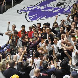 Members of the Lone Peak basketball team and student body surround team manager Tanner Payne as he hoists the state championship trophy after winning the state championship last March at the Dee Events Center in Ogden.