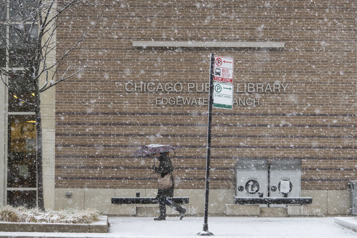 A woman uses an umbrella to shield herself from snow Dec. 28 while she walks past the Edgewater Branch of the Chicago Public Library.