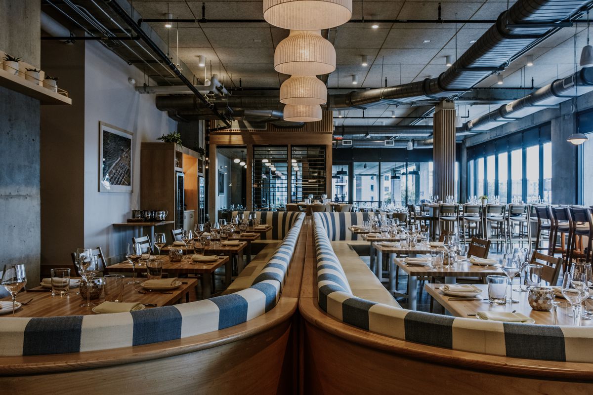 The dining room at Indaco Atlanta features a white and blue color scheme with long banquettes in the middle. 