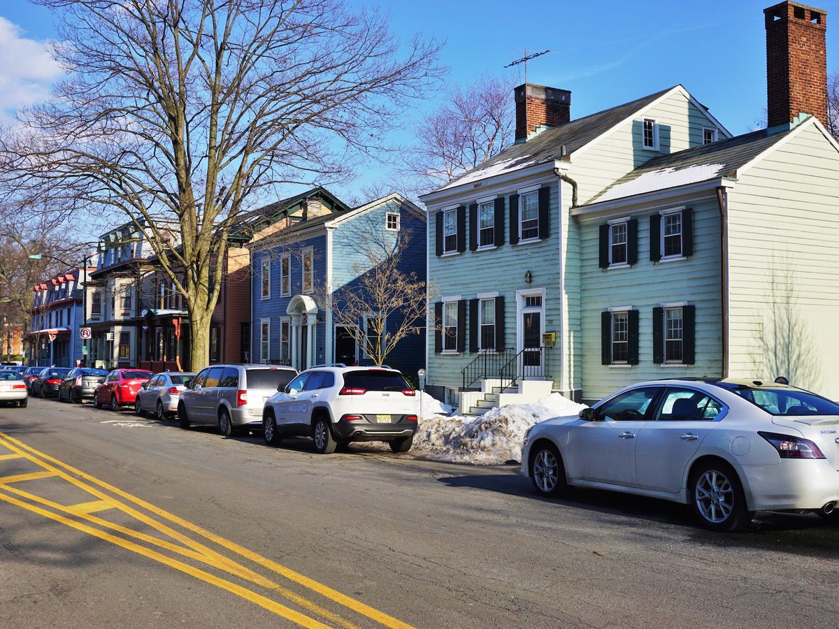 A row of houses. Cars are parked on the street in front of the houses. 