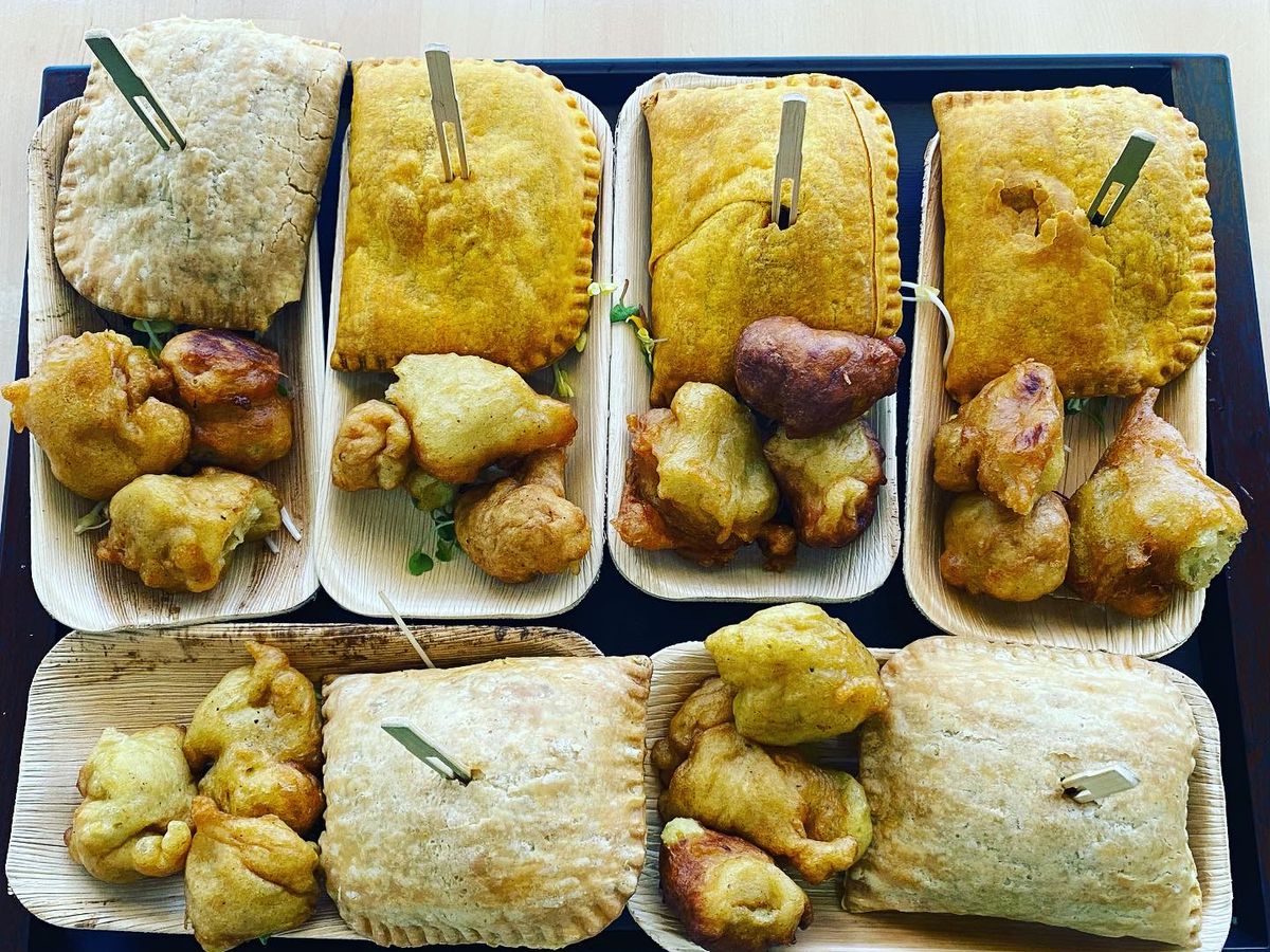 Several small trays of Jamaican patties and split pea fritters