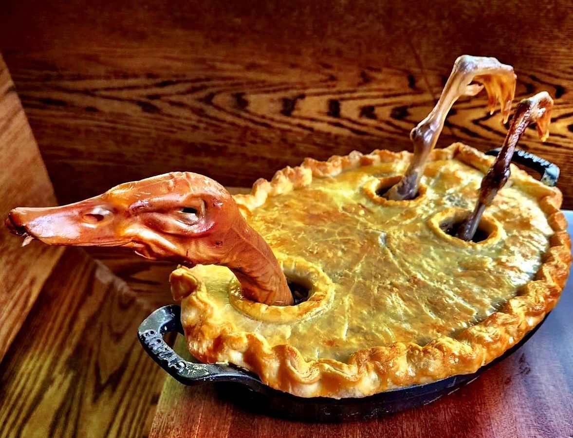 A meaty pie with the head and legs of a roast duck sticking out. 