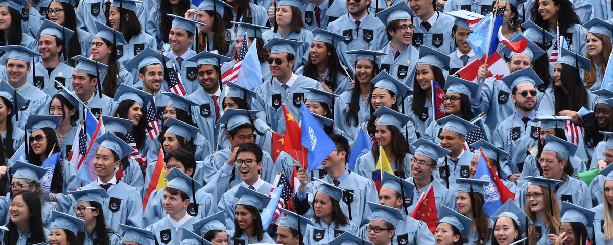 Columbia University graduates wear blue graduation robes and caps.