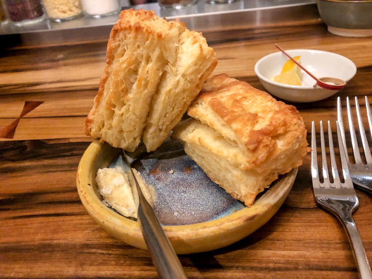 Two biscuits arranged on a small serving dish with a pat of fluffy butter on the side.