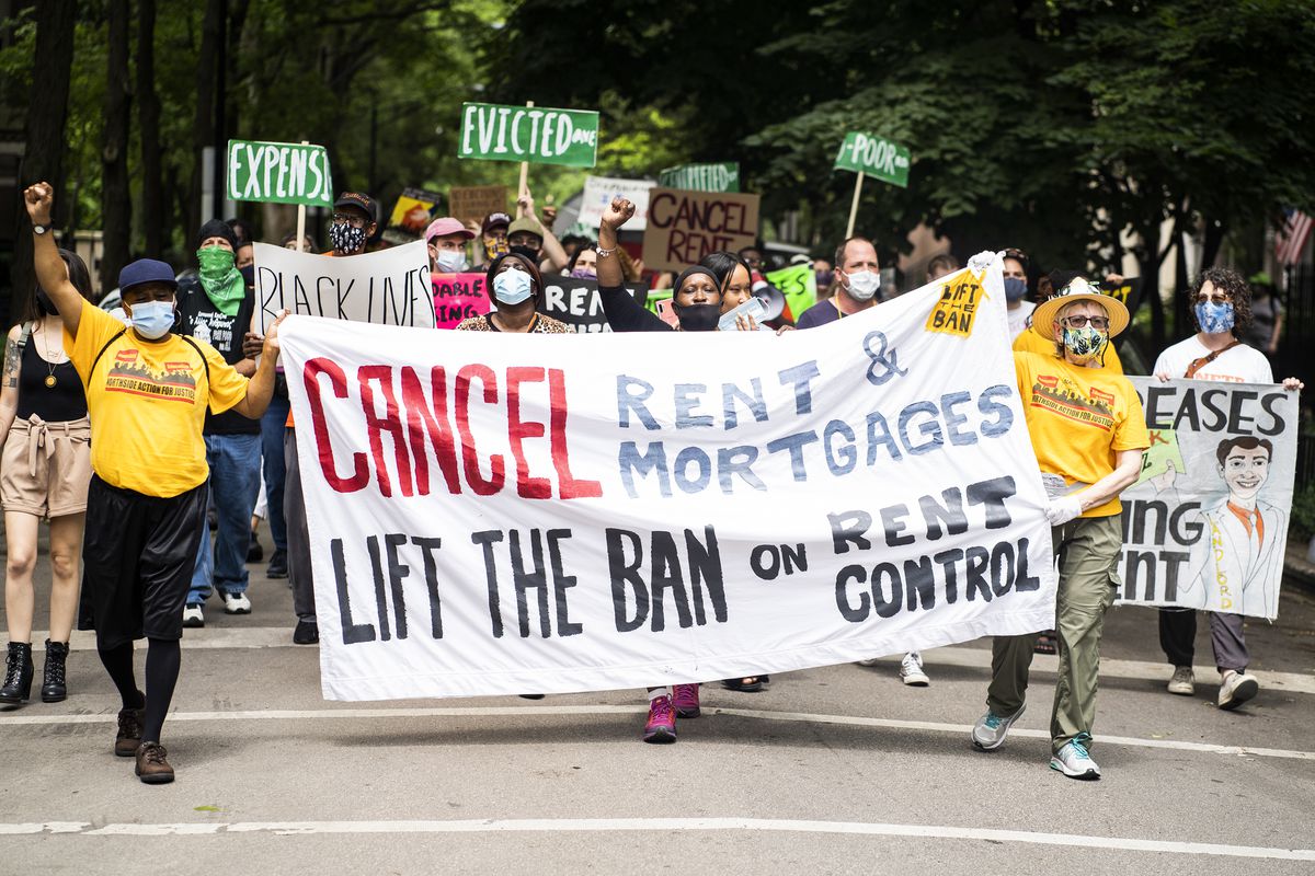 Protesters march and carry a banner that reads, “Cancel rent and mortgages. Lift the ban on rent control.”